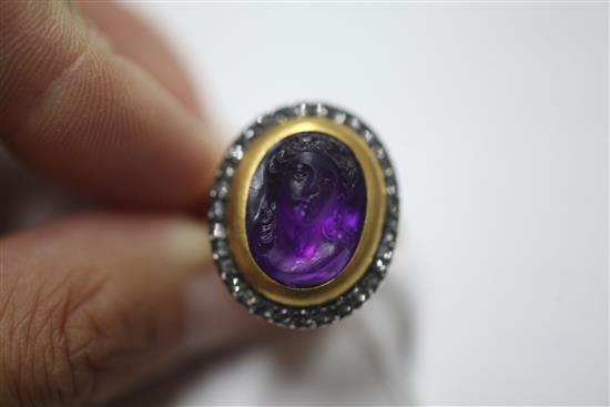 A 19th century amethyst glass? oval cameo ring, with rose cut diamond set border, (adapted?), size M.